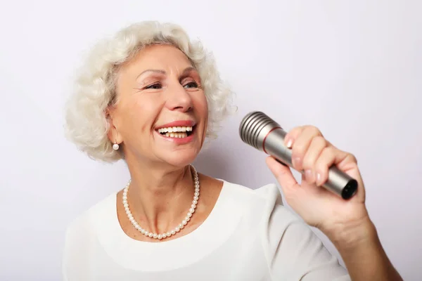 Estilo de vida y el concepto de la gente: Retrato de la encantadora abuela moderna sostiene el soporte del micrófono y canta — Foto de Stock