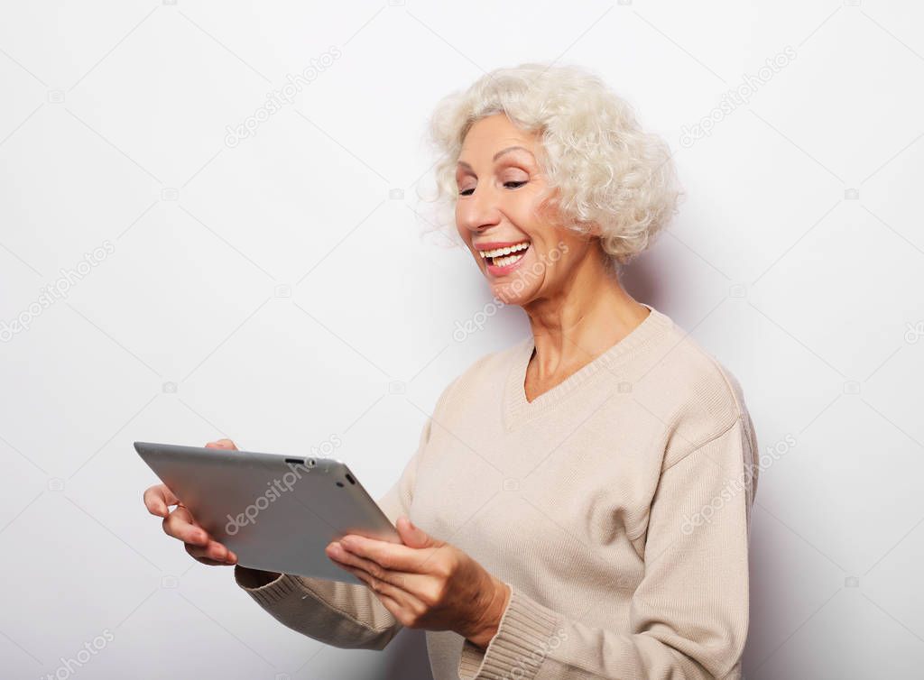 Happy mature woman using a tablet, communicates with children and grandchildren