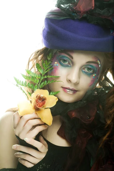 Młody model w sukience karnawałowej z kreatywnym makijażem. — Zdjęcie stockowe