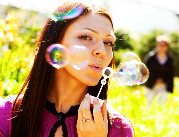 Girl blow soap bubble against a background grass — Stock Photo, Image