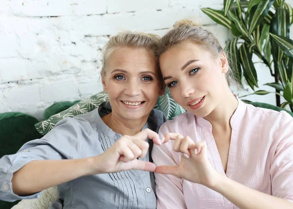 Mother and daughter love. Adult woman and young woman stacking hands in heart sign looking at camera. — Stock Photo, Image