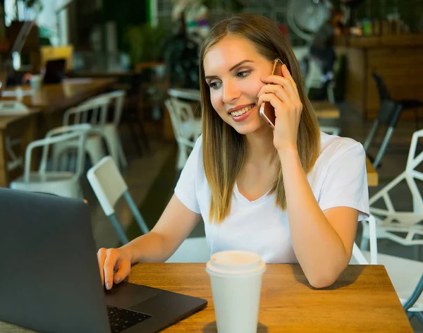 Gyönyörű szőke kislány ül egy kávézóban, és dolgozik a számítógép. — Stock Fotó