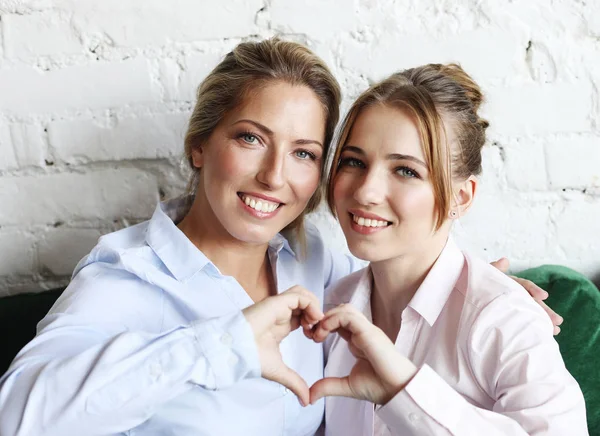 Femme adulte et jeune femme empilant les mains dans le signe du cœur en regardant la caméra . — Photo