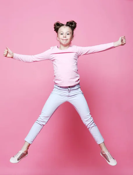 Divertente bambino ragazza vestito casual salto su sfondo rosa — Foto Stock