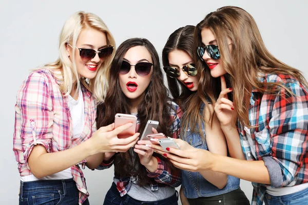 Tehnology, emoção e conceito de pessoas: quatro mulheres felizes amigos compartilhando mídias sociais em um telefone inteligente — Fotografia de Stock