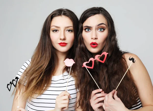 Dos chicas sexy con estilo mejores amigos sosteniendo palos de fiesta de papel —  Fotos de Stock