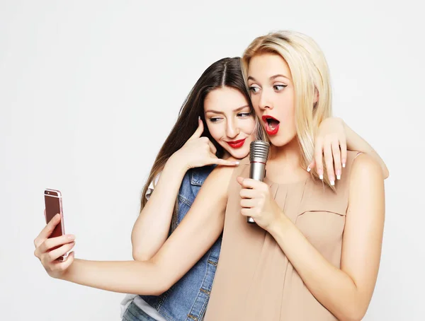 Две красавицы с микрофоном делают селфи со смартфоном — стоковое фото