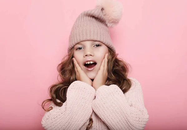 Menina criança vestindo chapéu de inverno rosa e suéter sobre fundo rosa, close-up — Fotografia de Stock