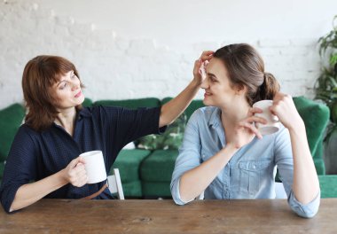 Güzel olgun anne ve yetişkin kızı kahve içiyorlar.