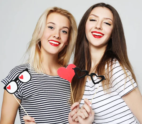Dos chicas sexy con estilo mejores amigos sosteniendo palos de fiesta de papel —  Fotos de Stock