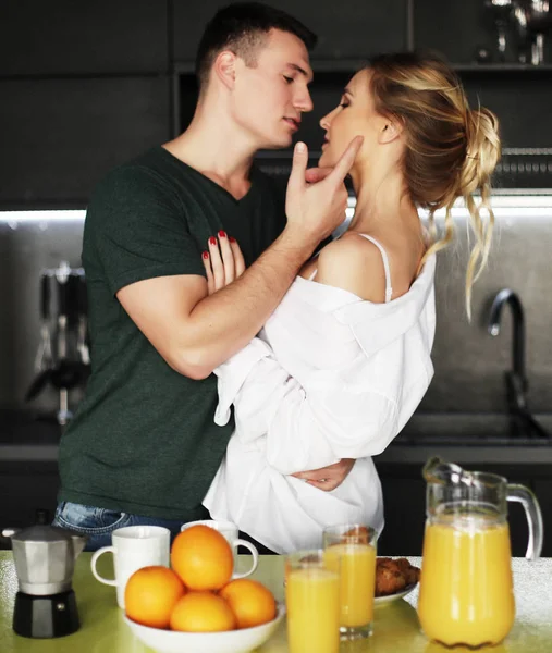 Lovely young couple standing and hugging on a kitchen at home — Stock Photo, Image