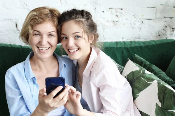 У віці жінка і її доросла дочка використовують смартфон вдома . — стокове фото