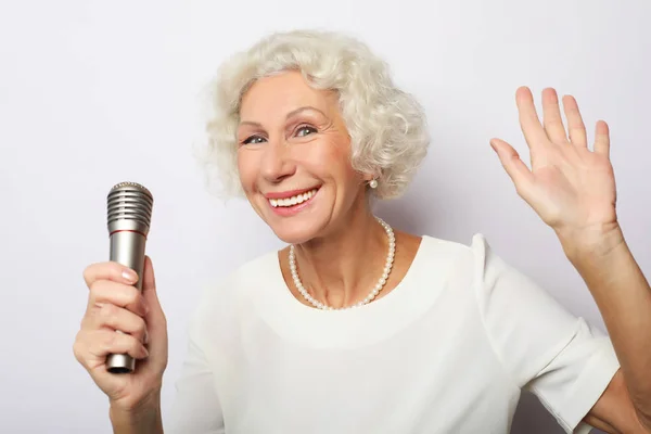 Retrato de la encantadora abuela moderna sostiene el micrófono — Foto de Stock