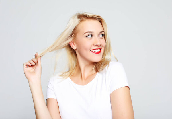 Beautiful happy girl touches her hair. Casual clothes.