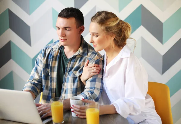 Portrait of a laughing loving couple having breakfast while sitting at the table in a kitchen — Stock Photo, Image