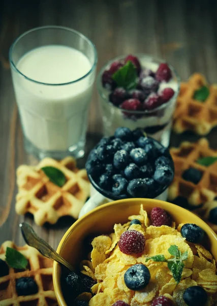 Pequeno-almoço saudável. Flocos de milho com framboesas e mirtilos, granola com iogurte e bagas, bolachas e leite . — Fotografia de Stock