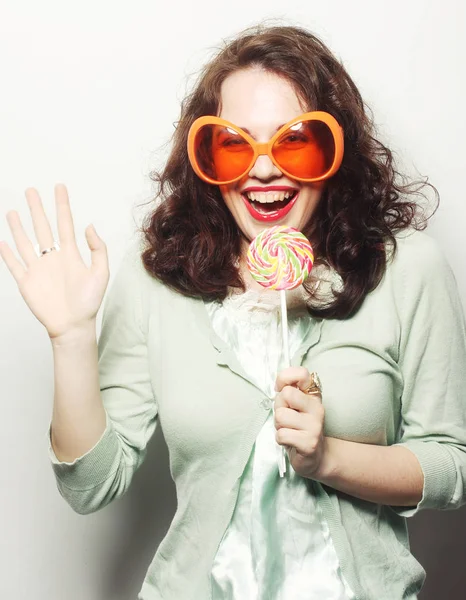 Vrouw in Groot oranje bril likken lolly met haar tong — Stockfoto