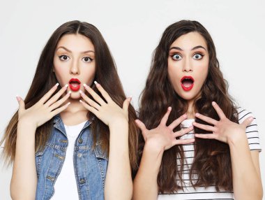 İki genç kız arkadaş eğleniyor. İkisi de şaşırmış suratlar yapıyor.