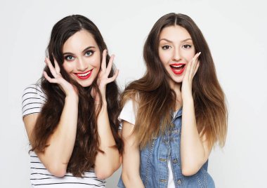 İki genç kız arkadaş eğleniyor. İkisi de şaşırmış suratlar yapıyor.