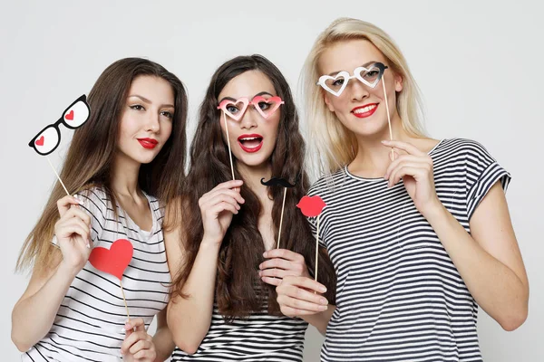 Tres mujeres jóvenes sosteniendo palos de fiesta de papel — Foto de Stock