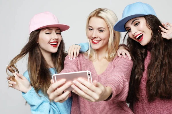 Tres felices mejores novias usando suéteres y gorras haciendo selfie — Foto de Stock