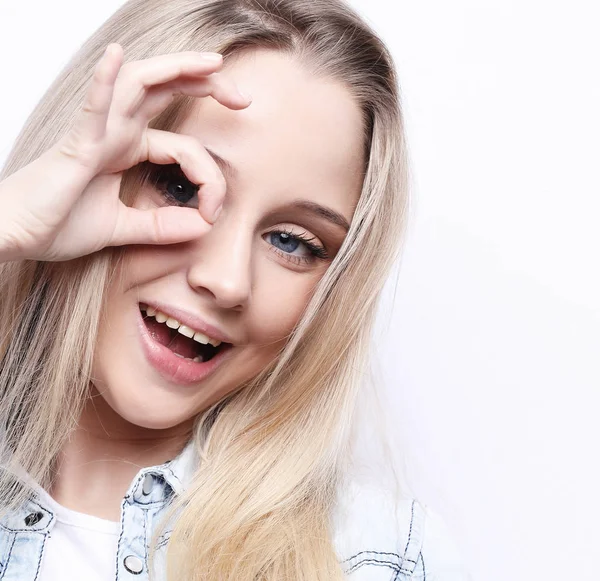 Mutlu heyecanlı genç kadın parmaklarını beyaz arka plan üzerinde yapılmış delikten bakarak yakın çekim