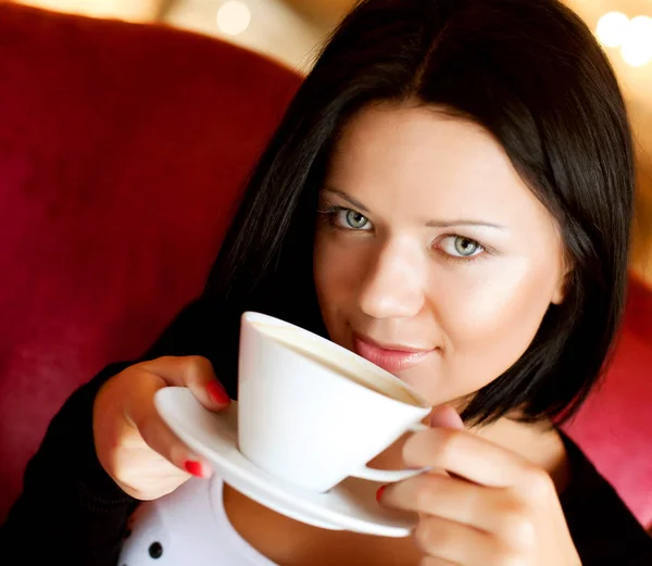 Молодая женщина, сидящая в кафе и пьющая кофе — стоковое фото