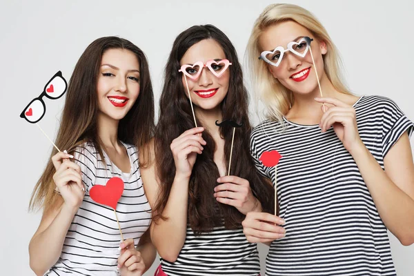 Tres mujeres jóvenes sosteniendo palos de fiesta de papel —  Fotos de Stock