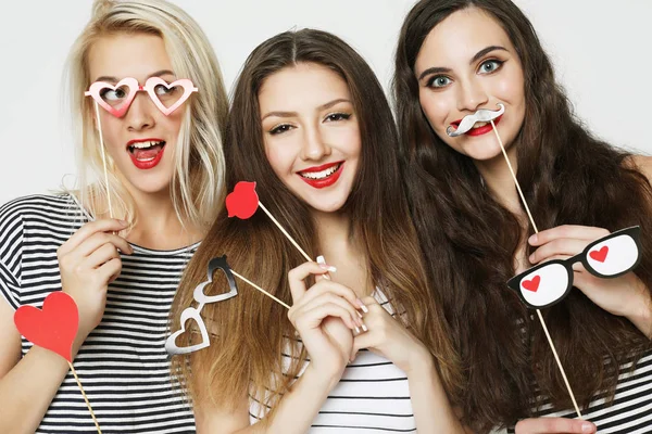 Tres mujeres jóvenes sosteniendo palos de fiesta de papel —  Fotos de Stock