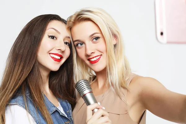 Två skönhetstjejer med mikrofon tar selfie med smartphone — Stockfoto