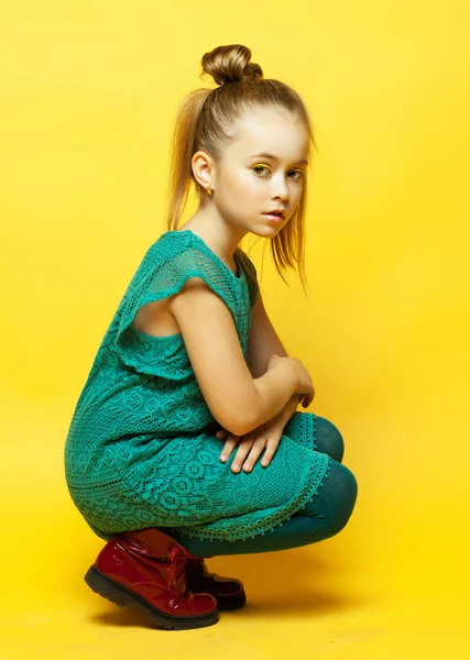 Pequena menina da moda com cabelo loiro posando sobre fundo amarelo — Fotografia de Stock