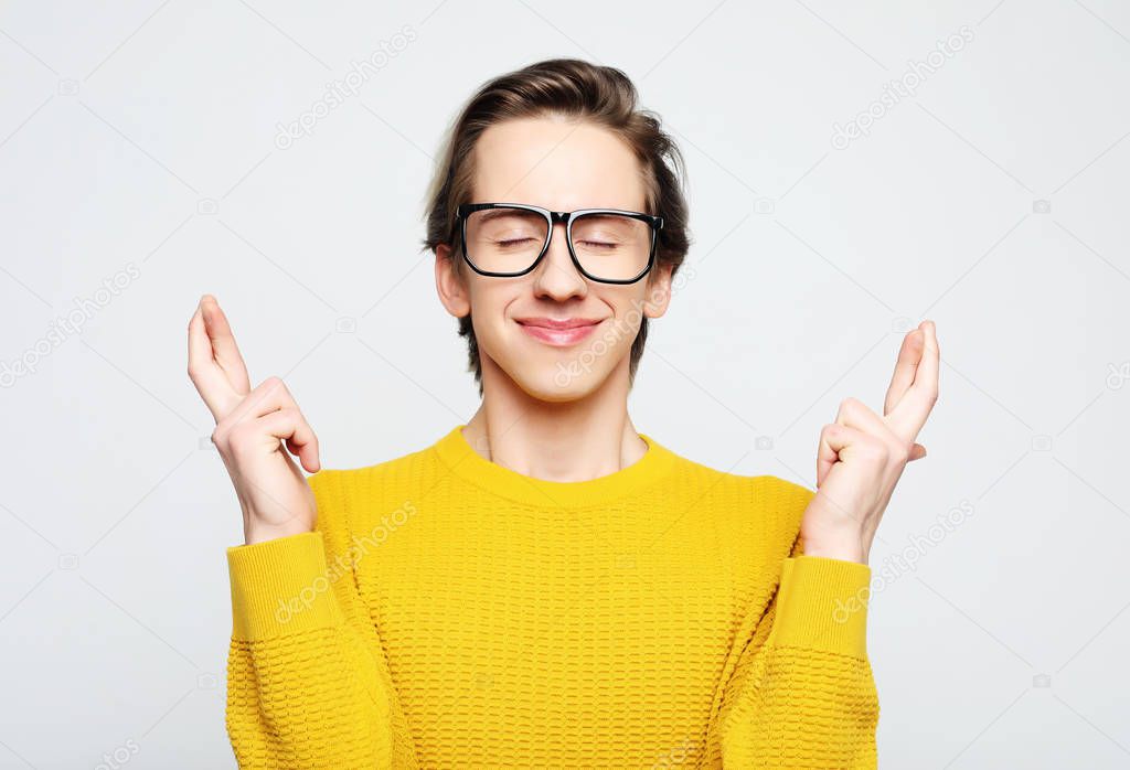  Portrait of charming caucasian man raising hands with crossed fingers and smiling