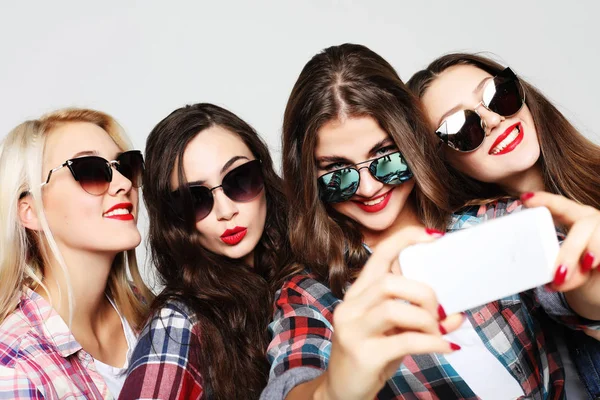 Четыре счастливые девочки-подростки со смартфоном делают селфи — стоковое фото