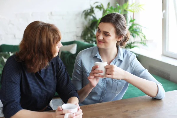 Beautiful mature mother and her adult daughter are drinking coffee — Stock Photo, Image