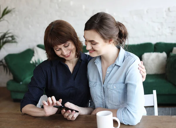 Mulher idosa e sua filha adulta usando smartphone em casa. — Fotografia de Stock