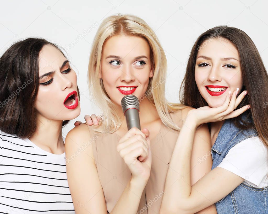 beauty girls with a microphone singing and having fun together 