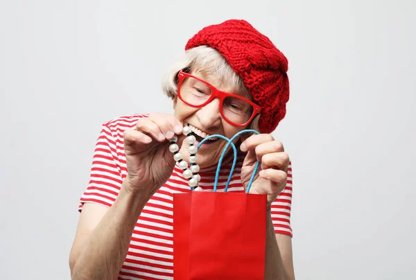 Životní styl a lidé koncept: starší žena vytáhne dárek z tašky — Stock fotografie