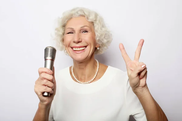 Retrato de la encantadora abuela moderna sostiene el soporte del micrófono y canta — Foto de Stock