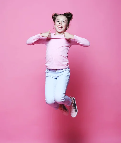 Drôle enfant fille habillé casual saut sur fond rose — Photo