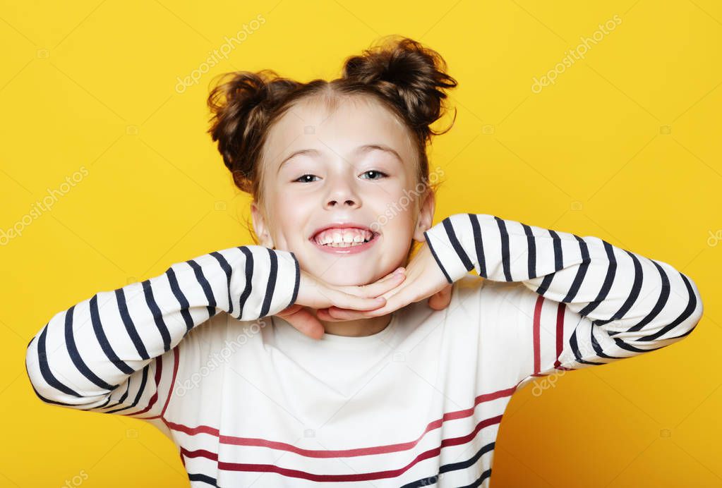 Portrait of cheerful smiling little girl on yellow background 