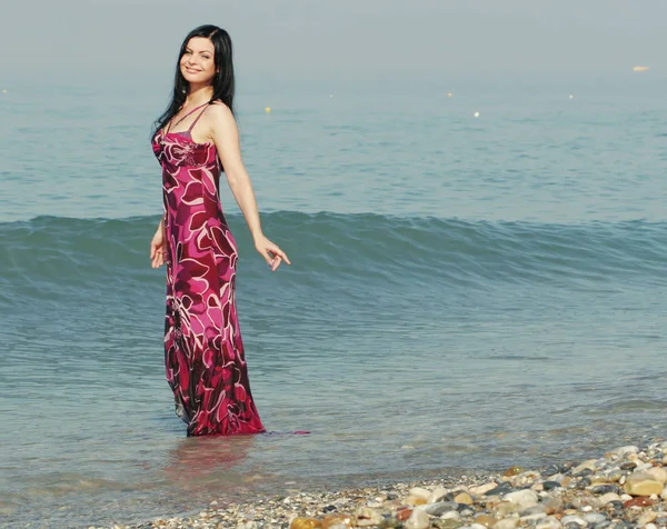 Frau im rosa Kleid am Meeresstrand — Stockfoto