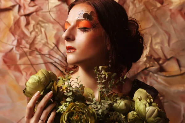 Frau mit leuchtendem, kreativem Make-up mit grünen Blumen — Stockfoto