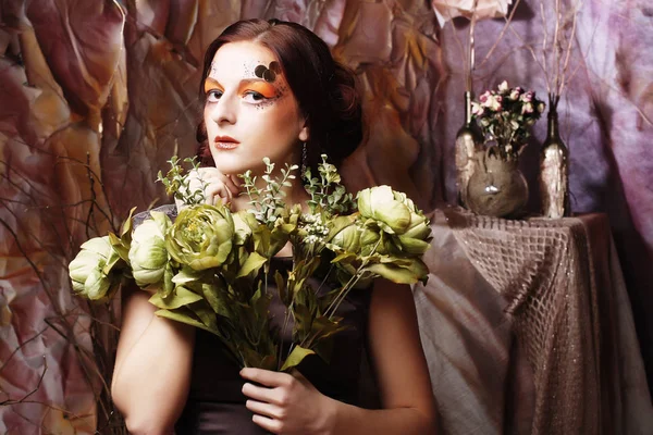 Frau mit leuchtendem, kreativem Make-up mit grünen Blumen — Stockfoto