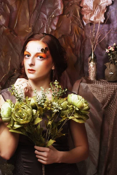 Mulher com brilhante criativo compõem segurando flores verdes — Fotografia de Stock