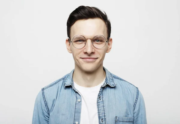 Retrato de um jovem inteligente vestindo óculos de pé contra fundo branco — Fotografia de Stock