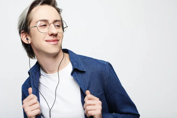 Jonge knappe man op witte studio achtergrond luisteren naar muziek op oortelefoons — Stockfoto