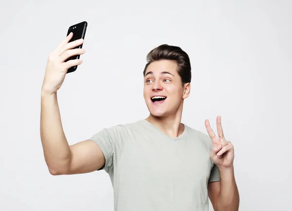 Foto de un hombre guapo sonriendo en la cámara tomando selfie — Foto de Stock