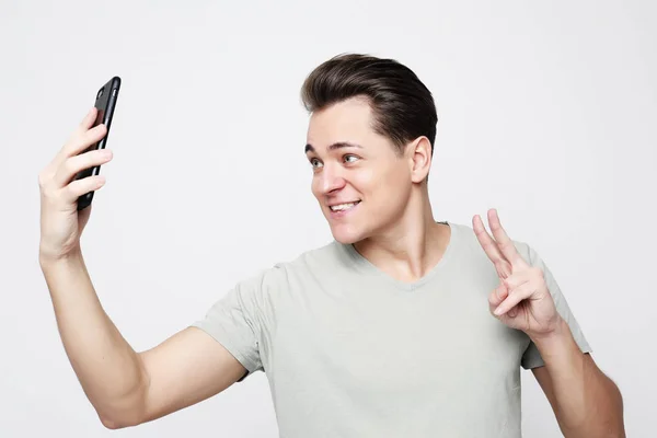 Foto de un hombre guapo sonriendo en la cámara tomando selfie — Foto de Stock