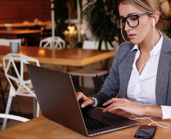 Mujer de negocios trabajando en el ordenador portátil en la cafetería. Mujer joven de negocios utiliza el ordenador portátil en la cafetería . — Foto de Stock