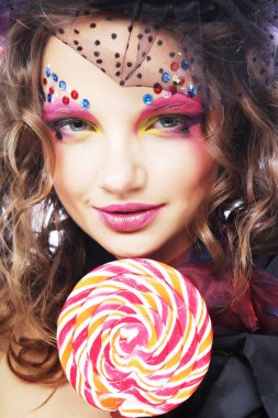 Yaratıcı makyajlı kız lolipop tutuyor. 